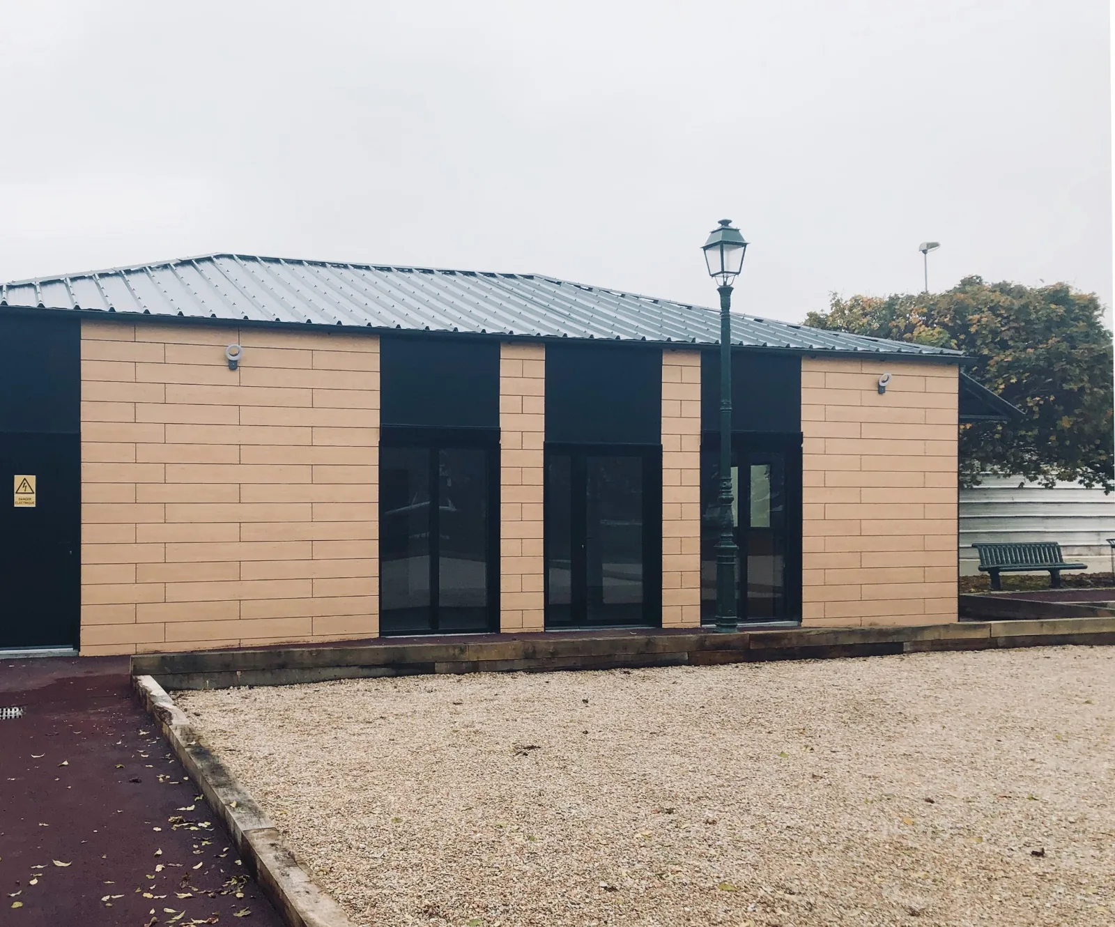 Façade en bardage aspect bois et baies vitrées du local des boulistes modulaire à Clamart